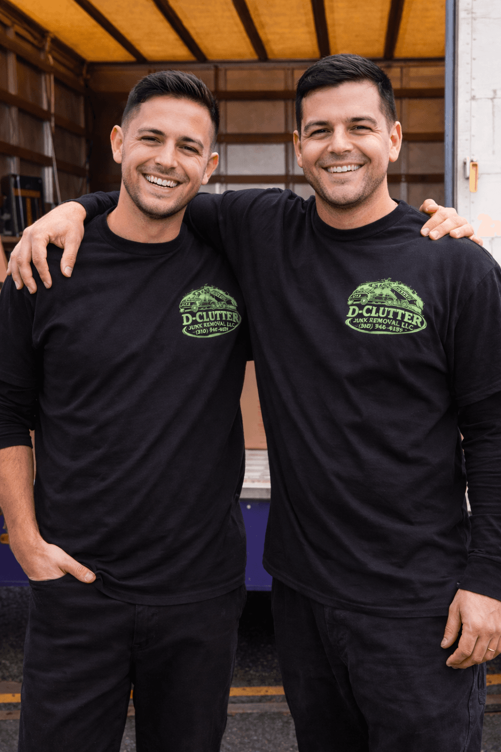 Happy D-CLUTTER Junk Removal team members smiling in front of their truck.